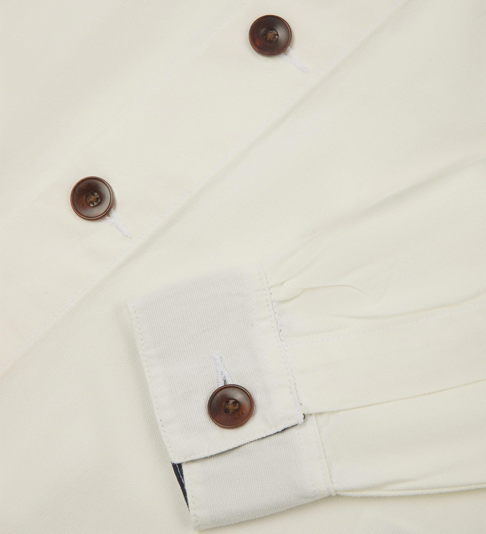 View of the mid-section and sleeve of the 3003 Uskees button-down work shirt in cream with focus on cuff, placket and corozo buttons.