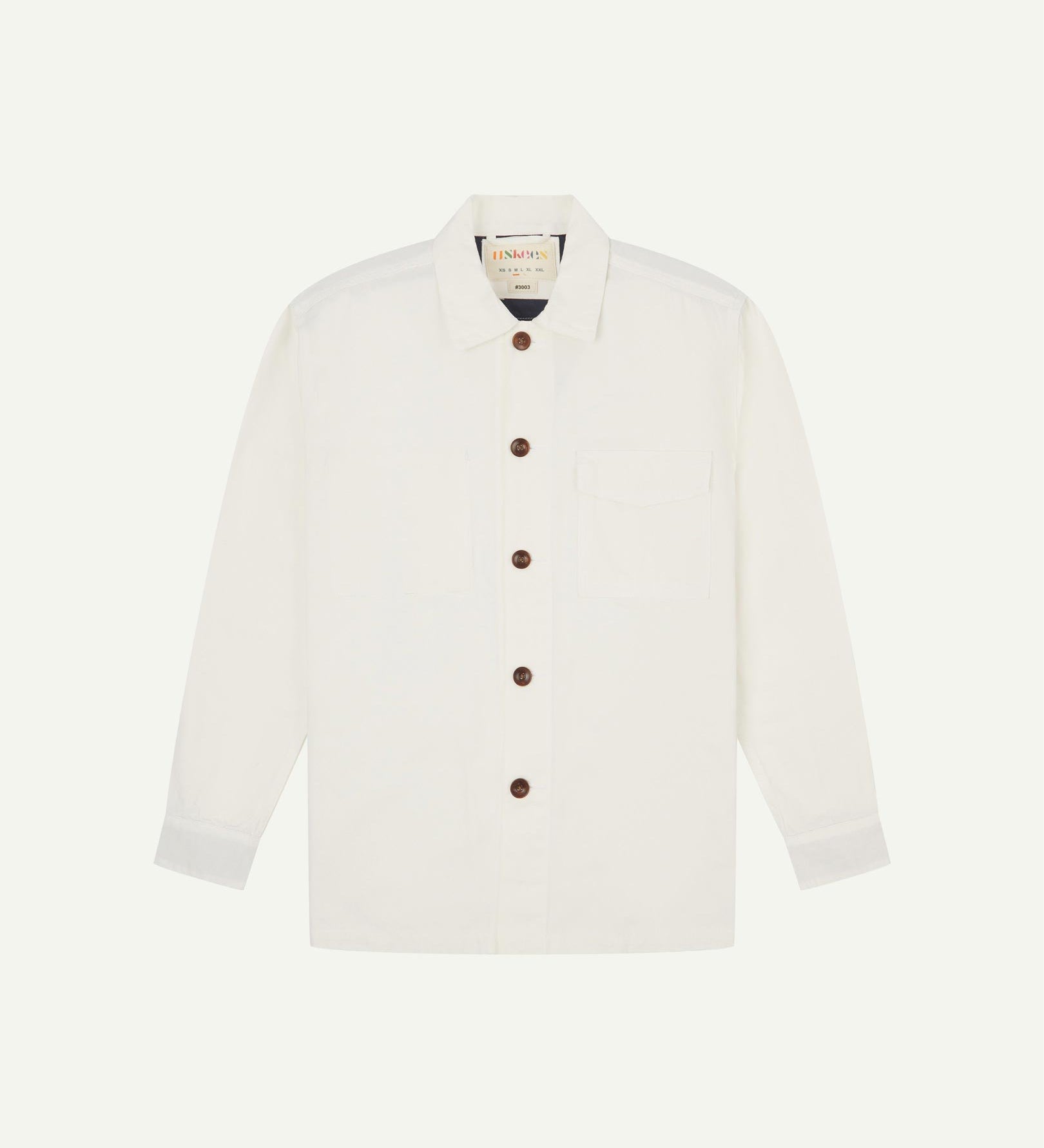 Cream buttoned organic cotton workshirt from Uskees with clear view of chest pocket and Uskees branding label.