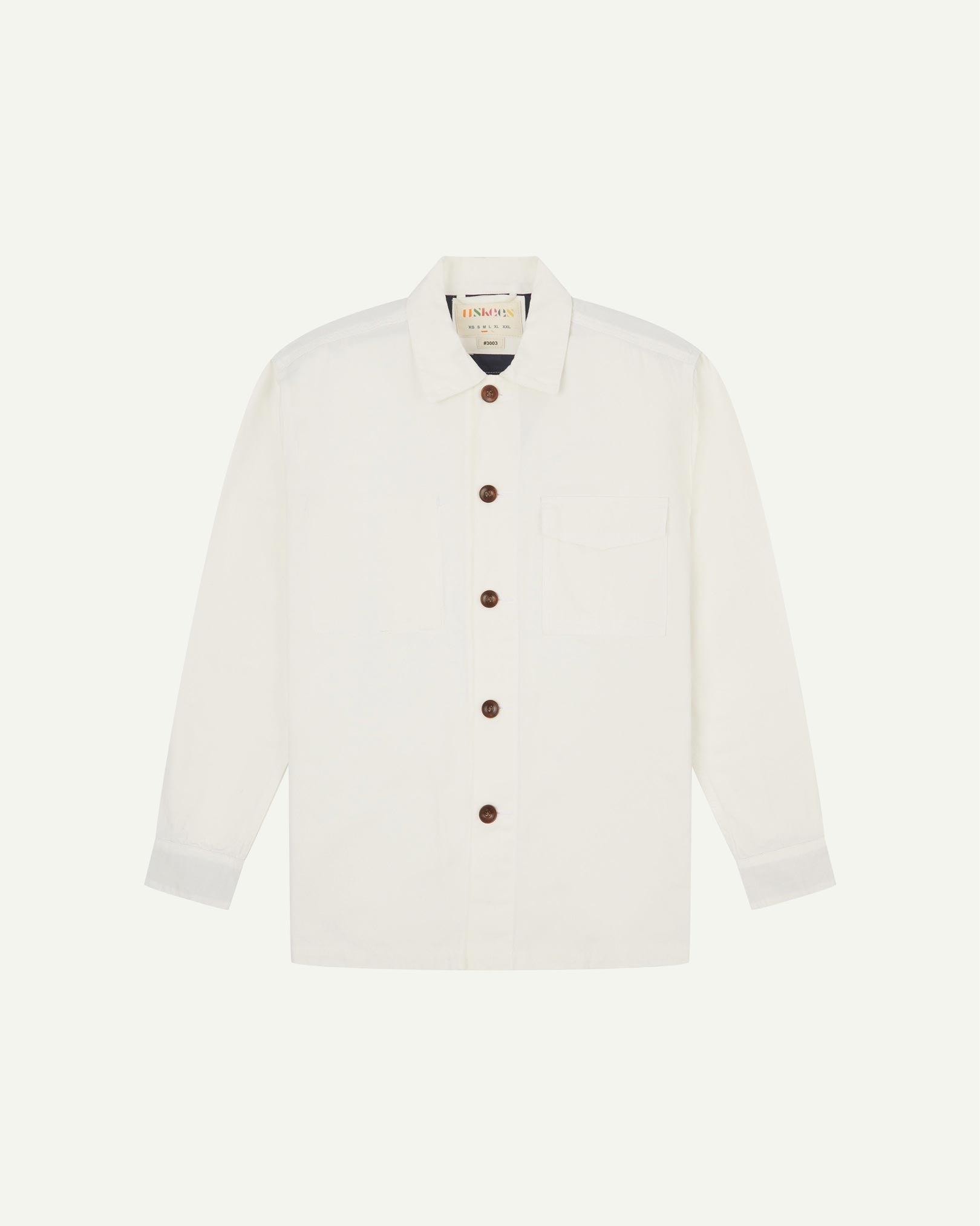 Cream buttoned organic cotton workshirt from Uskees with clear view of chest pocket and Uskees branding label.