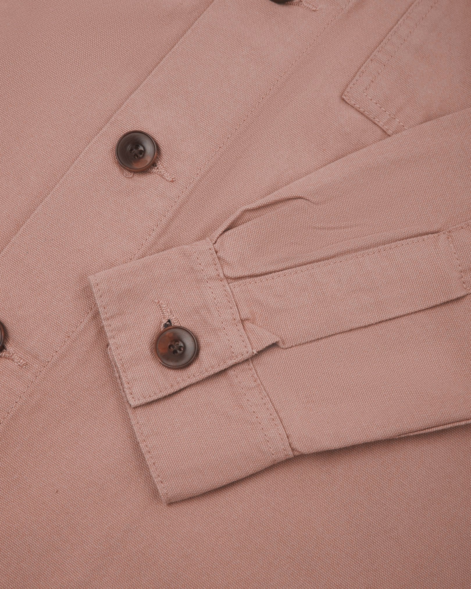 View of the mid-section and sleeve of the 3003 Uskees button-down work shirt in dusty pink with focus on cuff, placket and corozo buttons.