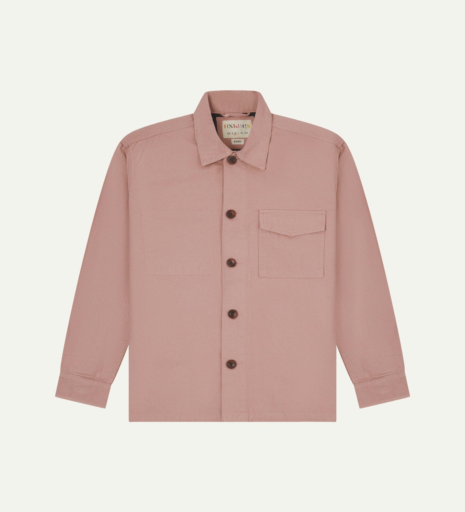 Front flat shot of pale pink buttoned 3003 workshirt from Uskees. Showing chest pocket with flap and corozo buttons.