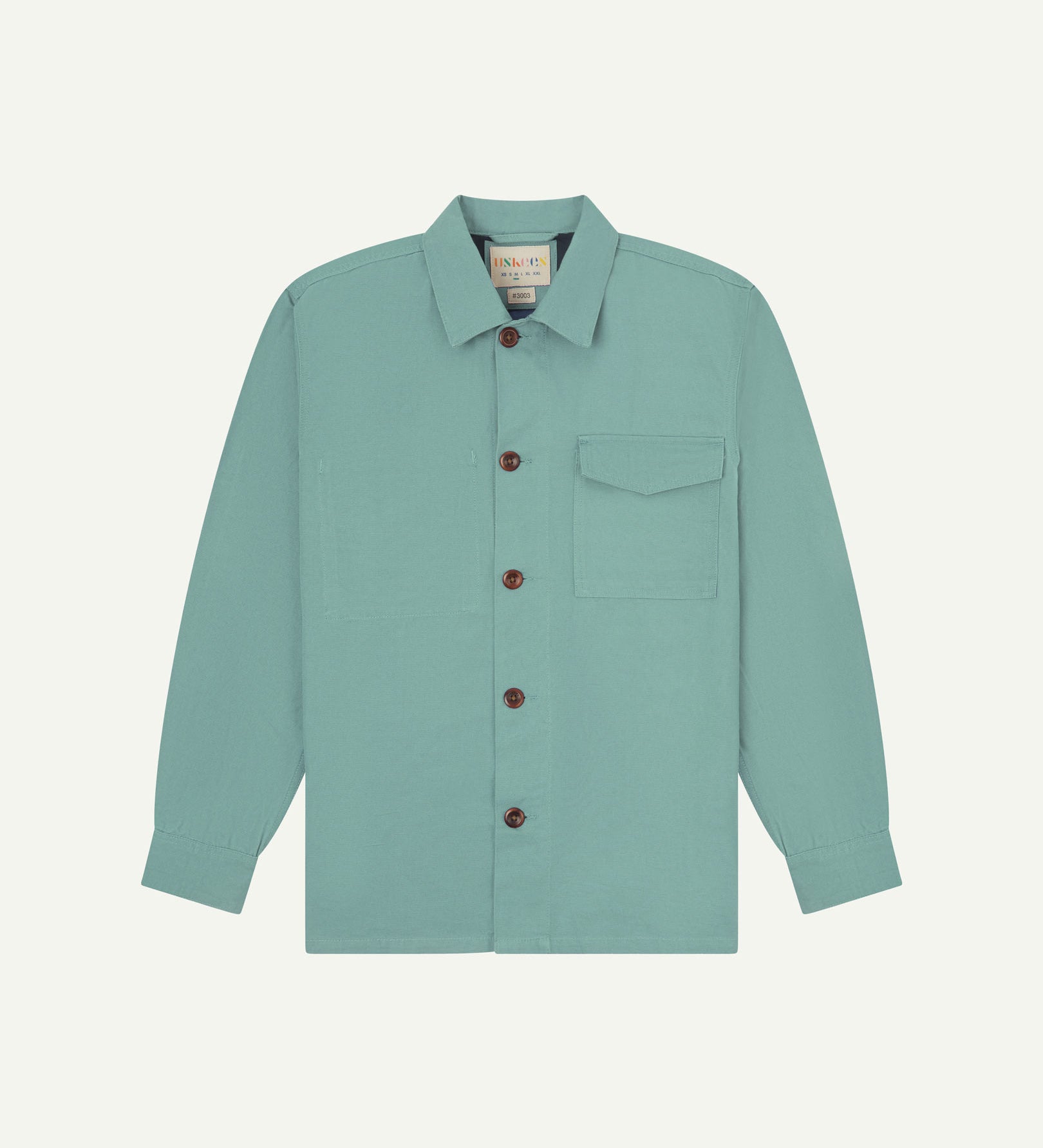 Eucalyptus (mint-green) buttoned organic cotton workshirt from Uskees with clear view of chest pocket and Uskees branding label.