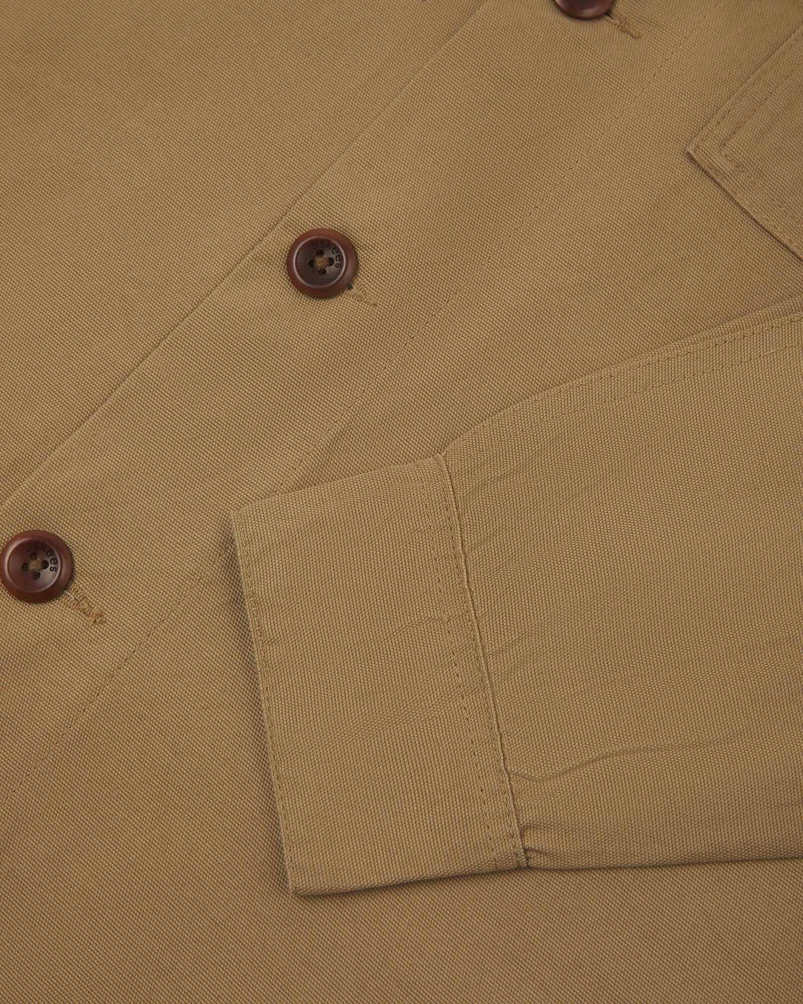 View of the mid-section and sleeve of the 3003 Uskees button-down work shirt in khaki with focus on cuff, placket and corozo buttons.