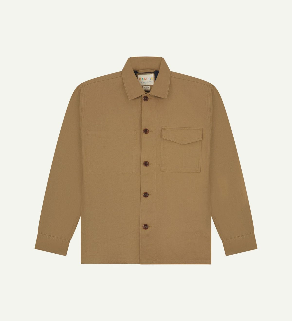 Khaki buttoned organic cotton workshirt from Uskees with clear view of chest pocket and Uskees branding label.