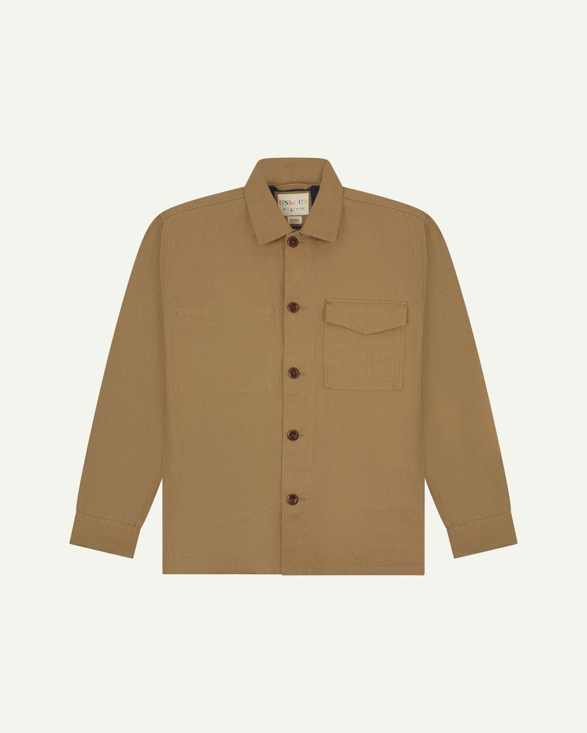 Khaki buttoned organic cotton workshirt from Uskees with clear view of chest pocket and Uskees branding label.