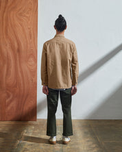 Back view of model wearing Uskees 3003 men's khaki workshirt showing reinforced elbow area and corozo buttoned cuffs.