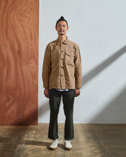 Full-length view of model wearing Uskees 3003 khaki workshirt illustrating utilitarian silhouette. Paired with Uskees matching pants.