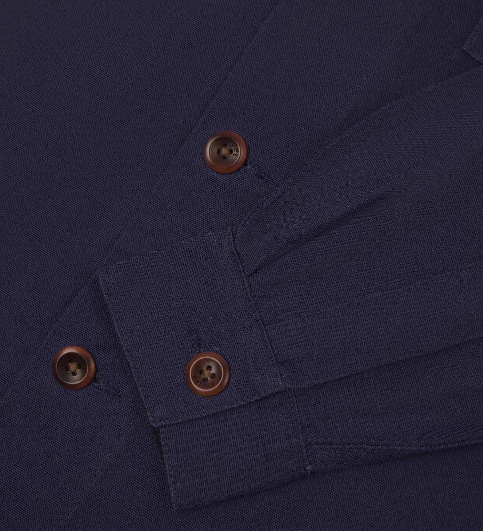 View of the mid-section and sleeve of the 3003 Uskees button-down work shirt in midnight blue with focus on cuff, placket and corozo buttons.