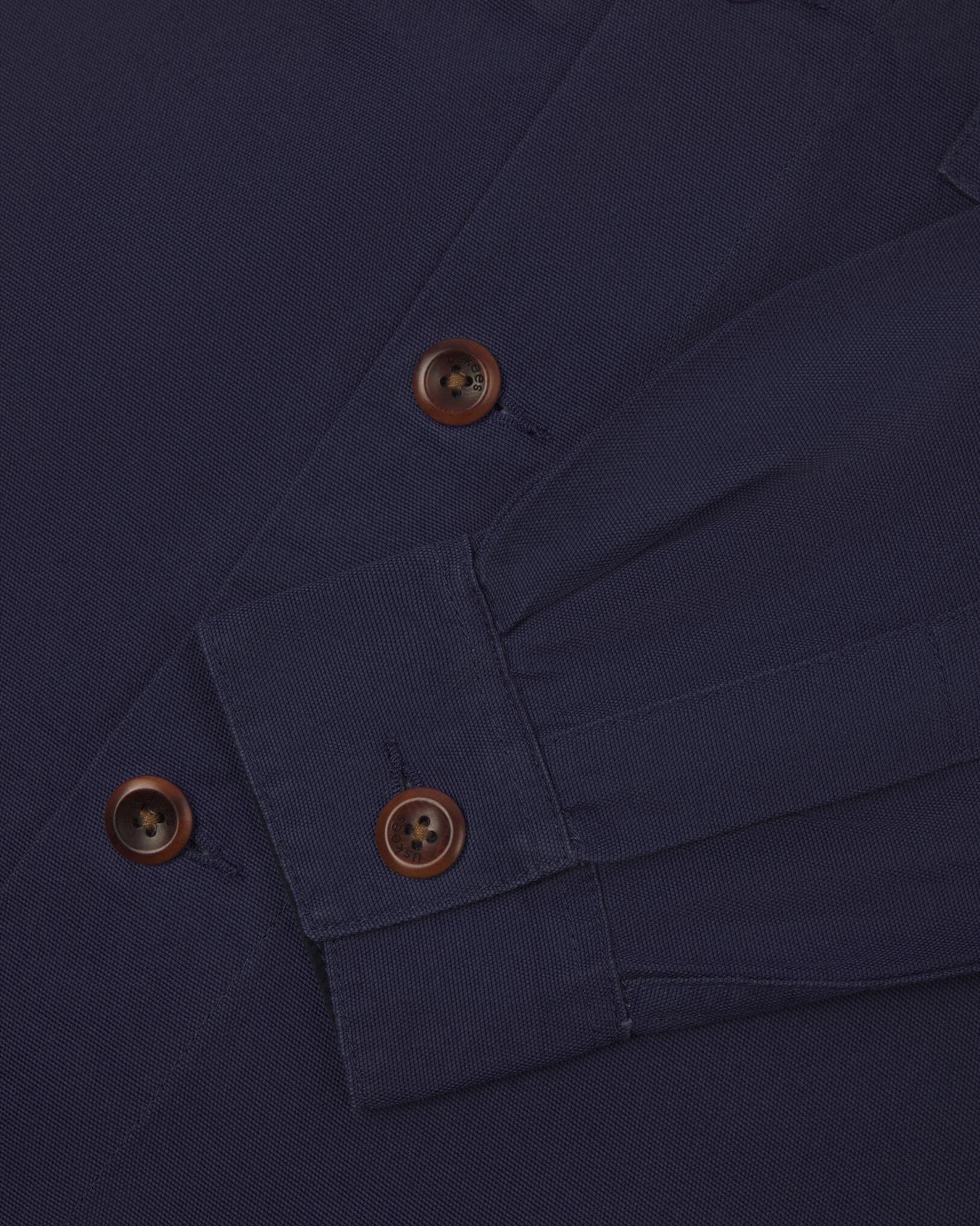 View of the mid-section and sleeve of the 3003 Uskees button-down work shirt in midnight blue with focus on cuff, placket and corozo buttons.