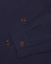 View of the mid-section and sleeve of the 3003 Uskees button-down work shirt in midnight blue with focus on cuff, placket and corozo buttons.