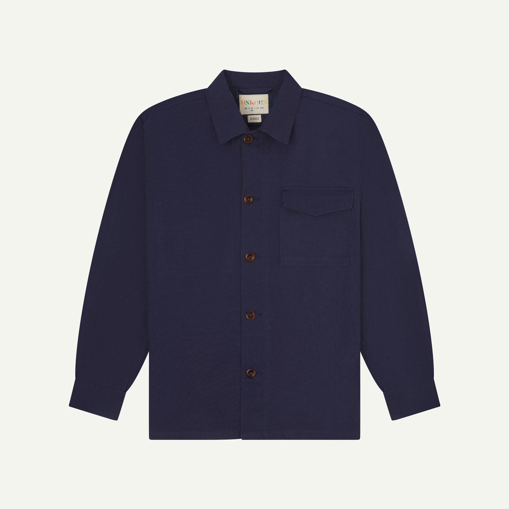 Midnight blue buttoned organic cotton workshirt from Uskees with clear view of chest pocket and Uskees branding label.