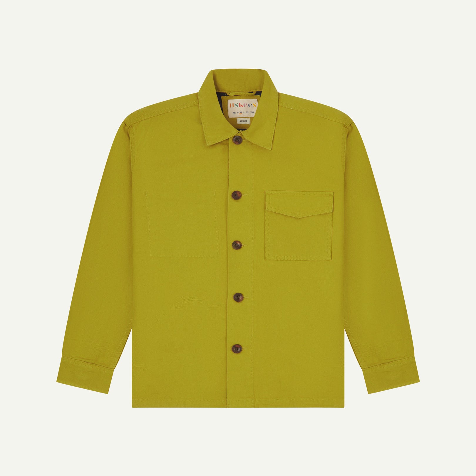 Yellow-green (pear) buttoned organic cotton workshirt from Uskees with clear view of chest pocket and Uskees branding label.