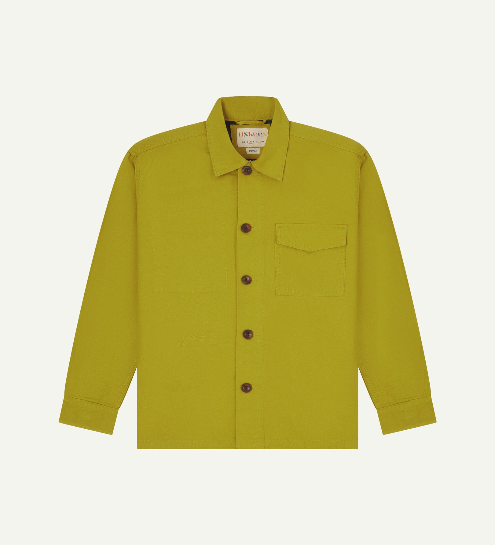 Yellow-green (pear) buttoned organic cotton workshirt from Uskees with clear view of chest pocket and Uskees branding label.
