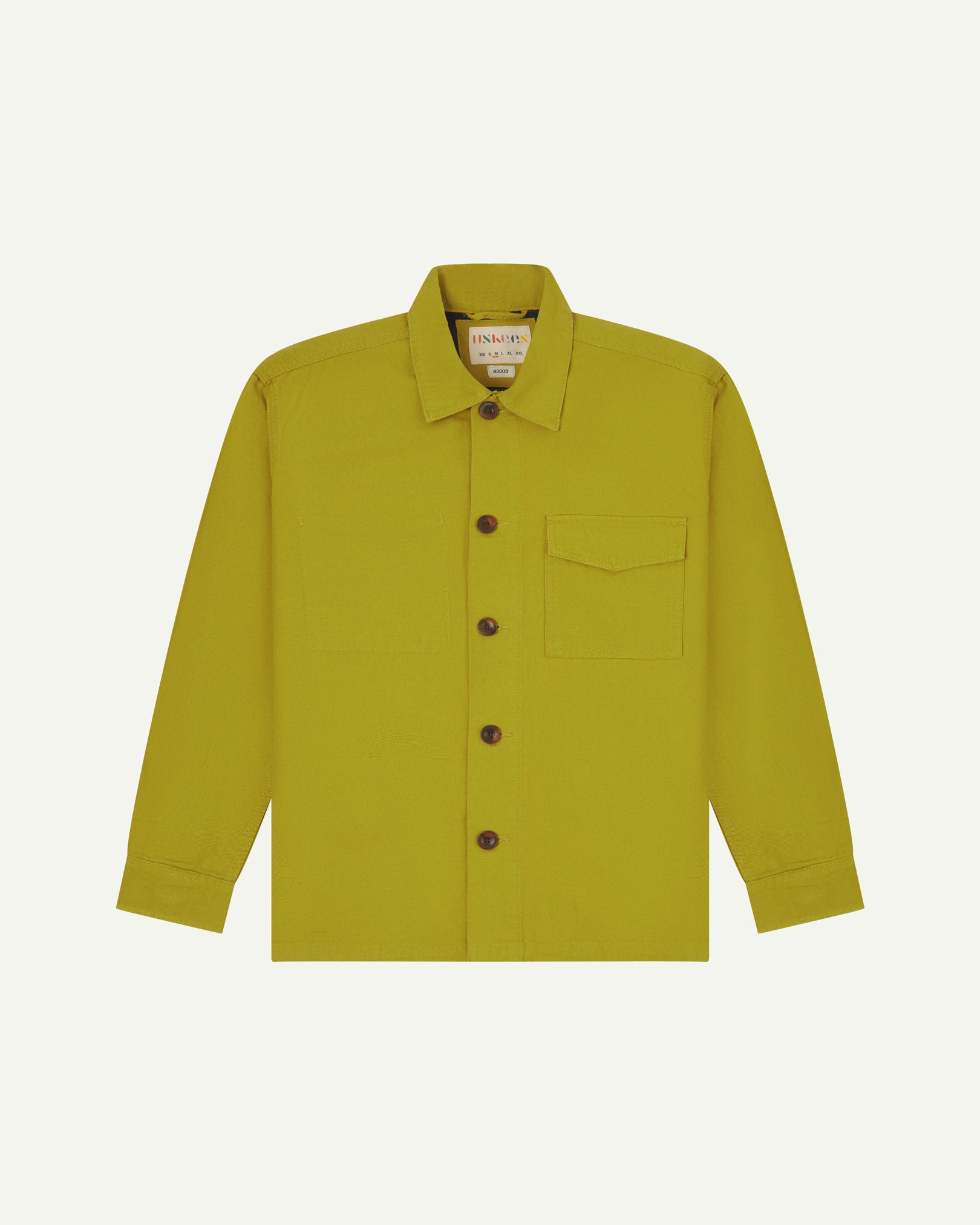 Yellow-green (pear) buttoned organic cotton workshirt from Uskees with clear view of chest pocket and Uskees branding label.