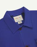 Close-up top-half view of #3003, ultra blue organic cotton workshirt. With focus on collar, Uskees brand label and corozo buttons.