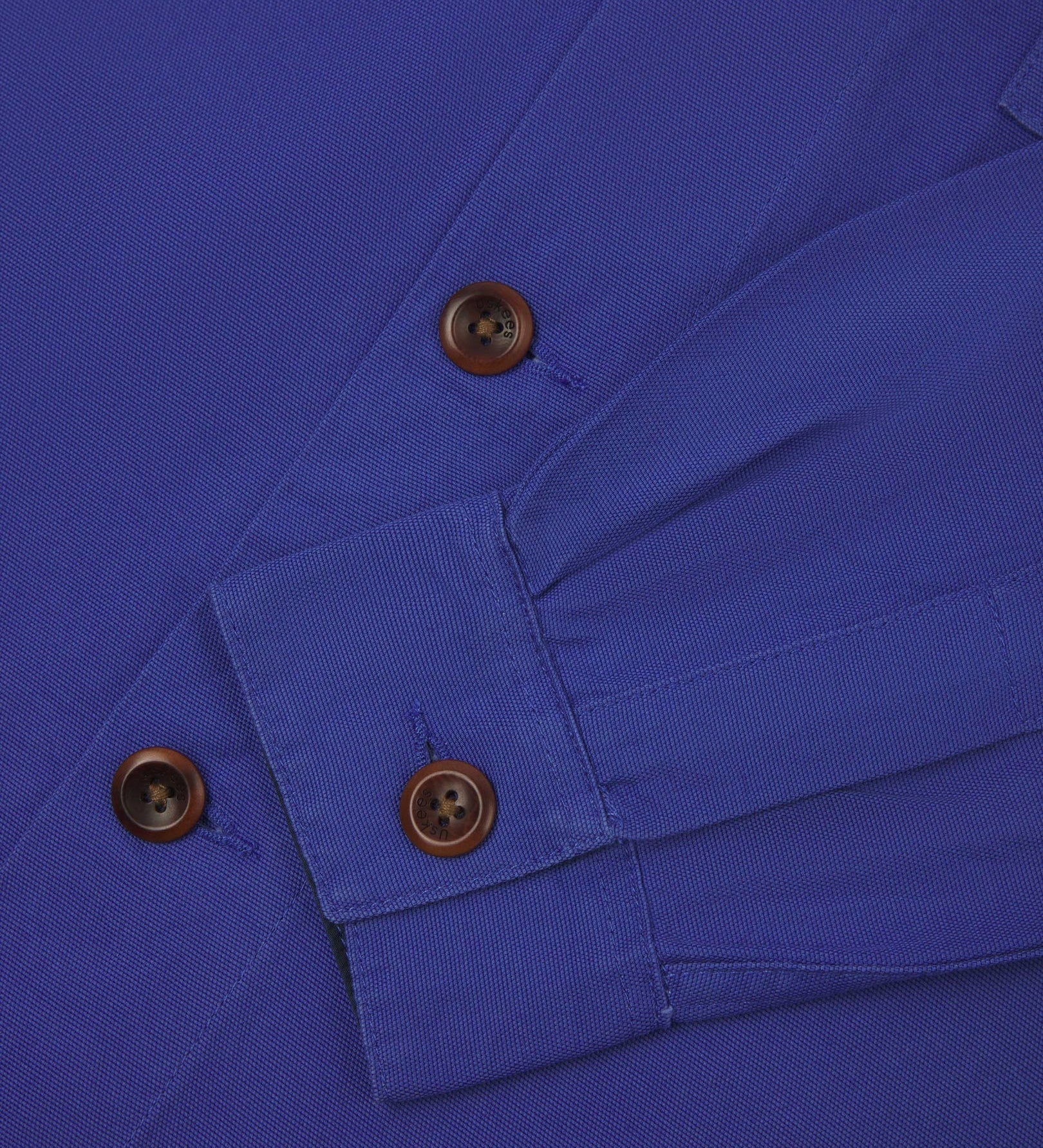 View of the mid-section and sleeve of the 3003 Uskees button-down work shirt in ultra blue with focus on cuff, placket and corozo buttons.