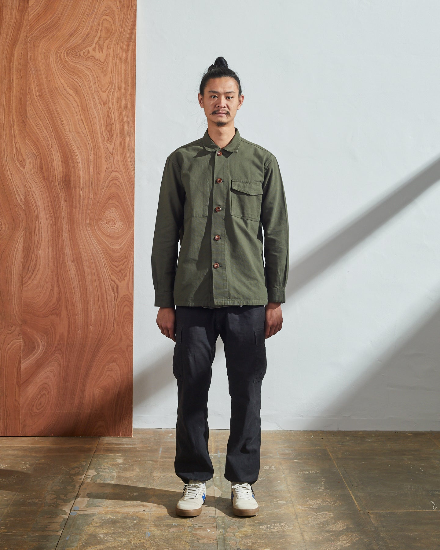 Full-length front view of model wearing Uskees buttoned work shirt in vine green, demonstrating boxy silhouette.