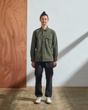 Full-length front view of model wearing Uskees buttoned work shirt in vine green, demonstrating boxy silhouette.