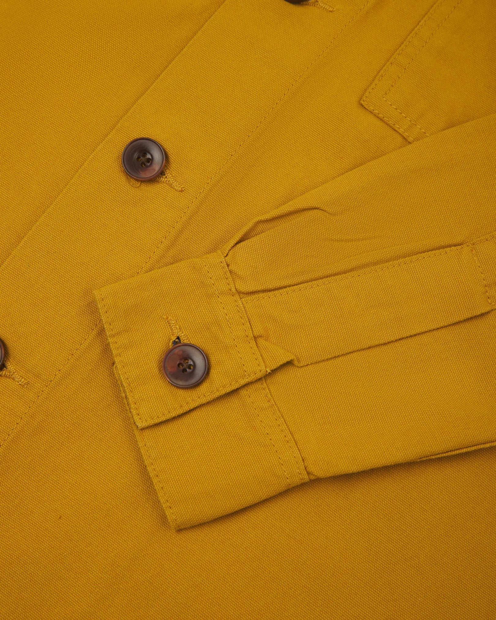 View of the mid-section and sleeve of the 3003 Uskees button-down work shirt in yellow with focus on cuff, placket and corozo buttons.