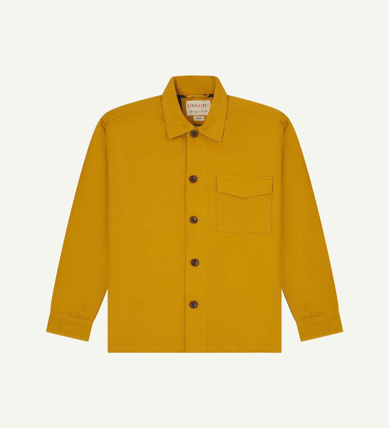 Yellow buttoned organic cotton workshirt from Uskees with clear view of chest pocket and Uskees branding label.