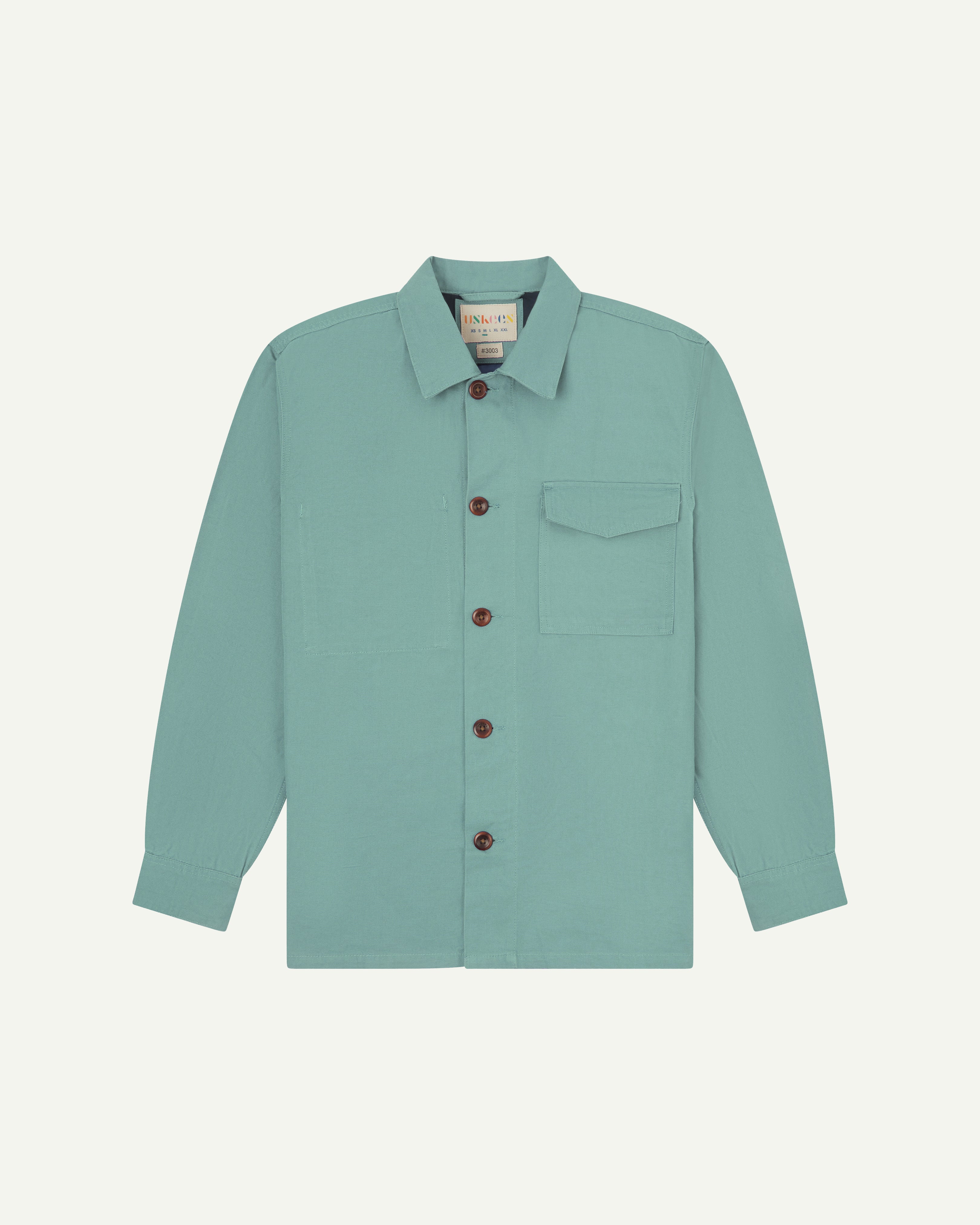 Front flat shot of pale green #3003 workshirt from Uskees. Showing chest pocket with flap and corozo buttons.