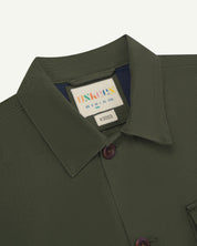 Front close shot of dull green #3003 men's workshirt from Uskees. Showing collar, brand/size label  and corozo buttons.