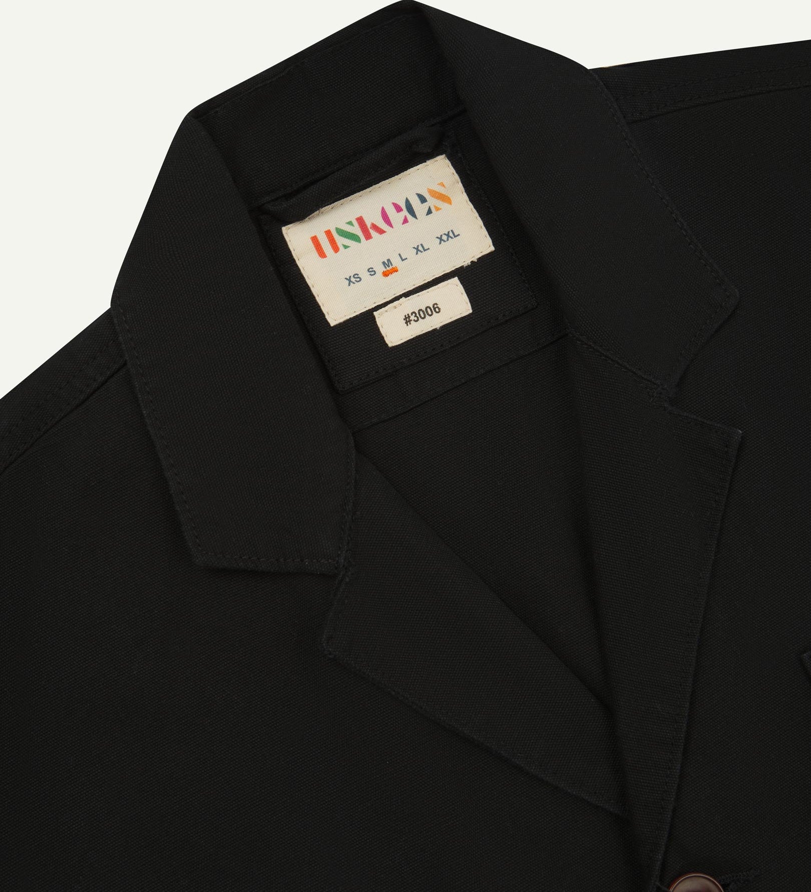 Close-up front view of organic cotton black blazer showing the collar, lapels and Uskees brand label.