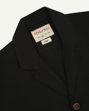 Close-up front view of organic cotton black blazer showing the collar, lapels and Uskees brand label.