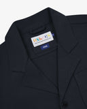 Close-up top-half view of #3006, dark blue (blueberry) organic cotton-drill blazer. With focus on collar, lapels, Uskees brand label and corozo buttons.