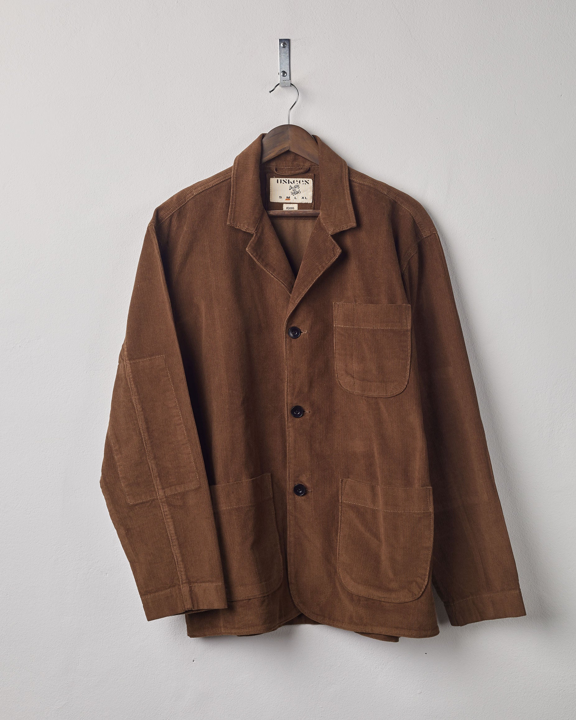 Front view of brown corduroy blazer with 3 patch pockets from Uskees. Presented on a hanger.