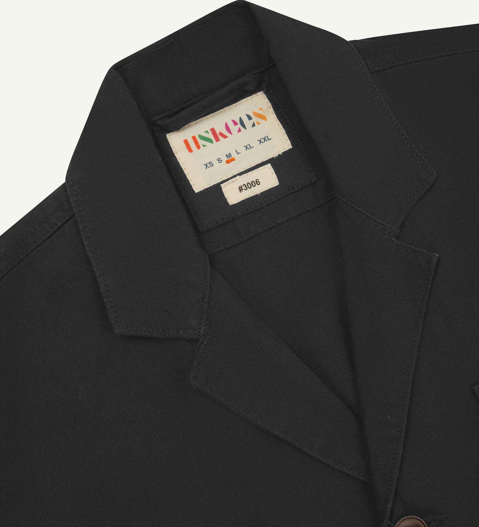 Close-up front view of organic cotton charcoal grey blazer showing the collar, lapels and Uskees brand label.