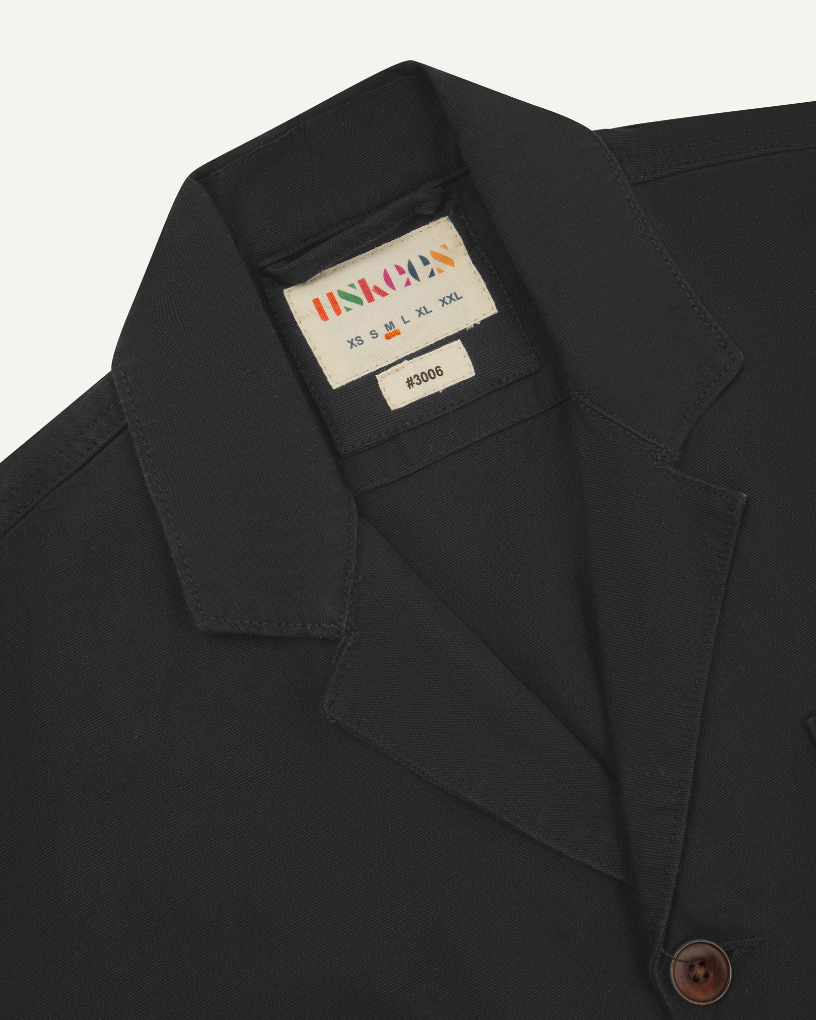 Close-up front view of organic cotton charcoal grey blazer showing the collar, lapels and Uskees brand label.