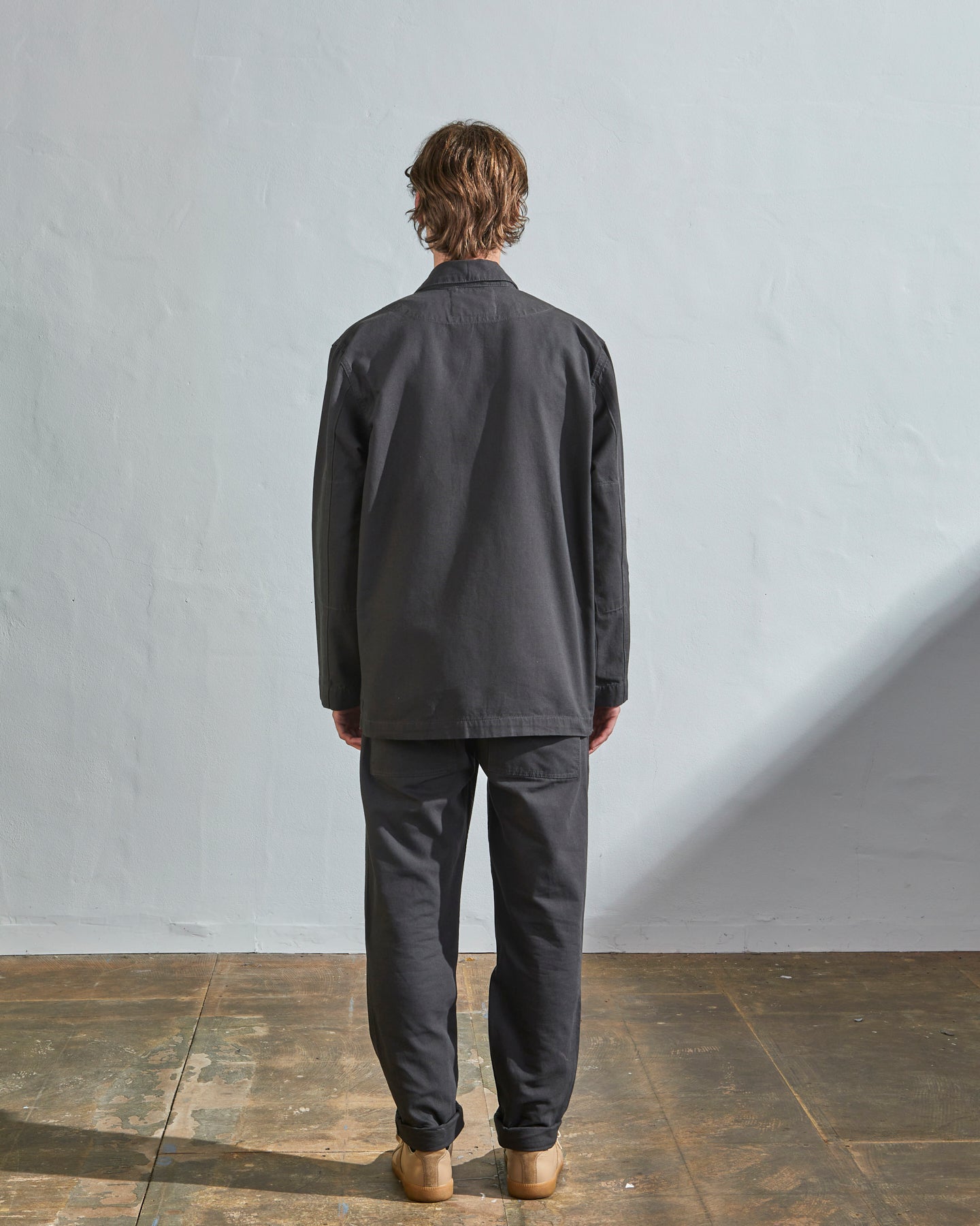 Full-length back view of model wearing 3006, charcoal blazer paired with matching Uskees pants and gold T-shirt.