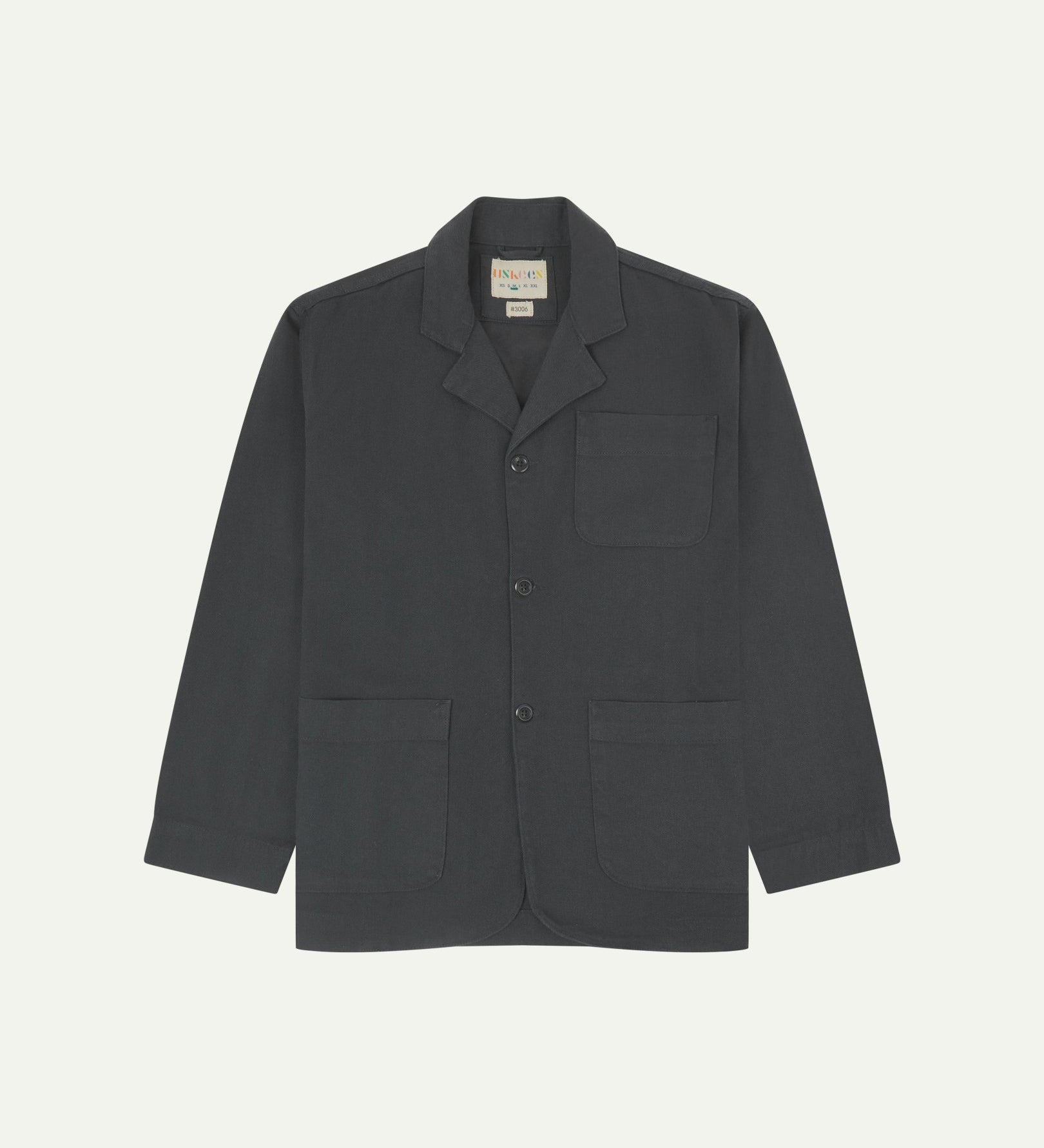 Charcoal-grey buttoned organic cotton-drill blazer from Uskees with clear view of three patch pockets and Uskees branding label.