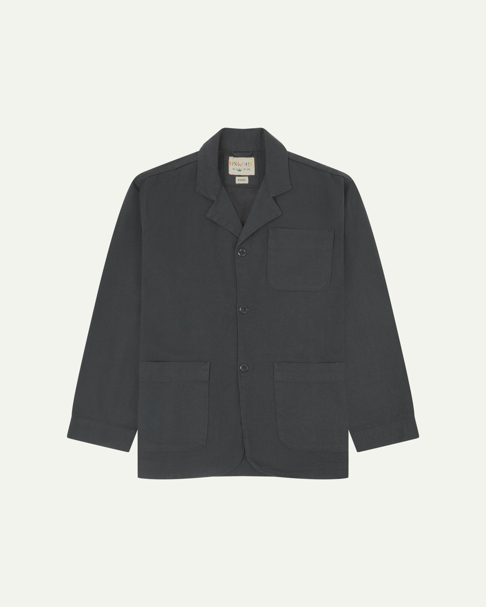 Charcoal-grey buttoned organic cotton-drill blazer from Uskees with clear view of three patch pockets and Uskees branding label.