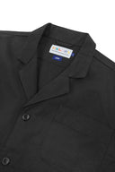 Angled top-half view of #3006, charcoal-grey organic cotton-twill blazer. With focus on collar, lapels, breast pocket, Uskees brand label and corozo buttons.