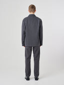 Full-length back view of man wearing charcoal-grey buttoned organic cotton-twill blazer paired with matching Uskees pants.