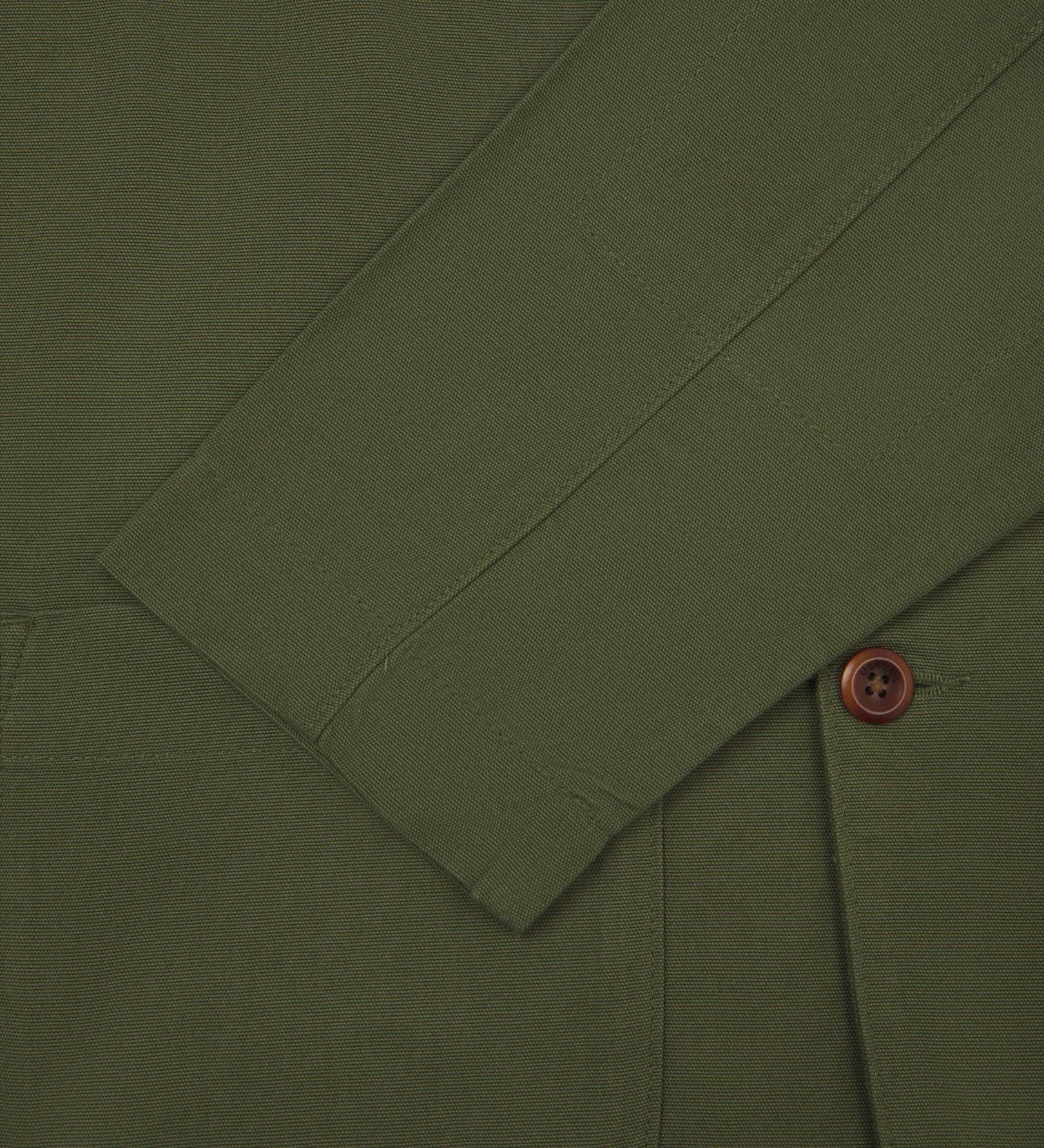 Close-up view of cuff and placket of organic cotton, coriander-green blazer from Uskees.