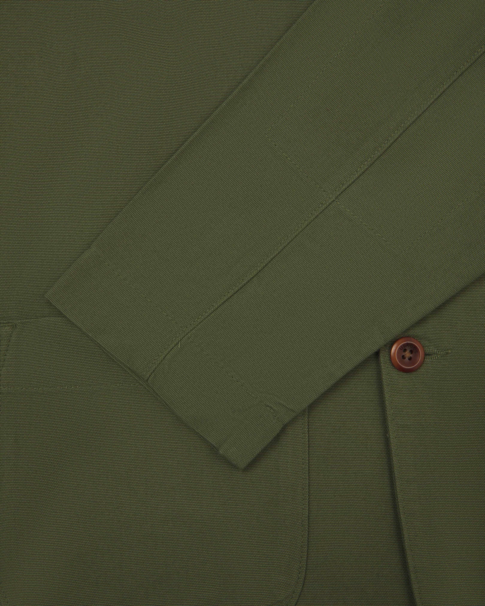 Close-up view of cuff and placket of organic cotton, coriander-green blazer from Uskees.