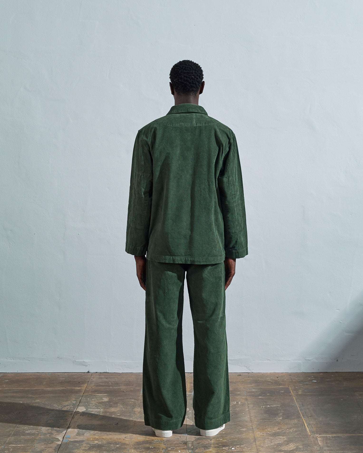 Full length back view of model wearing coriander-green corduroy #3006 Uskees blazer. Paired with Uskees coriander-green cord pants.
