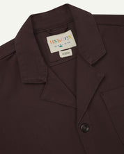 Close-up top-half view of #3006, burgundy-brown organic cotton-drill blazer. With focus on collar, lapels, Uskees brand label and corozo buttons.