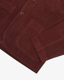Closer detail view of hip patch pocket, hemline and the extra durable weave of the organic cotton deep wine berry coloured corduroy fabric.