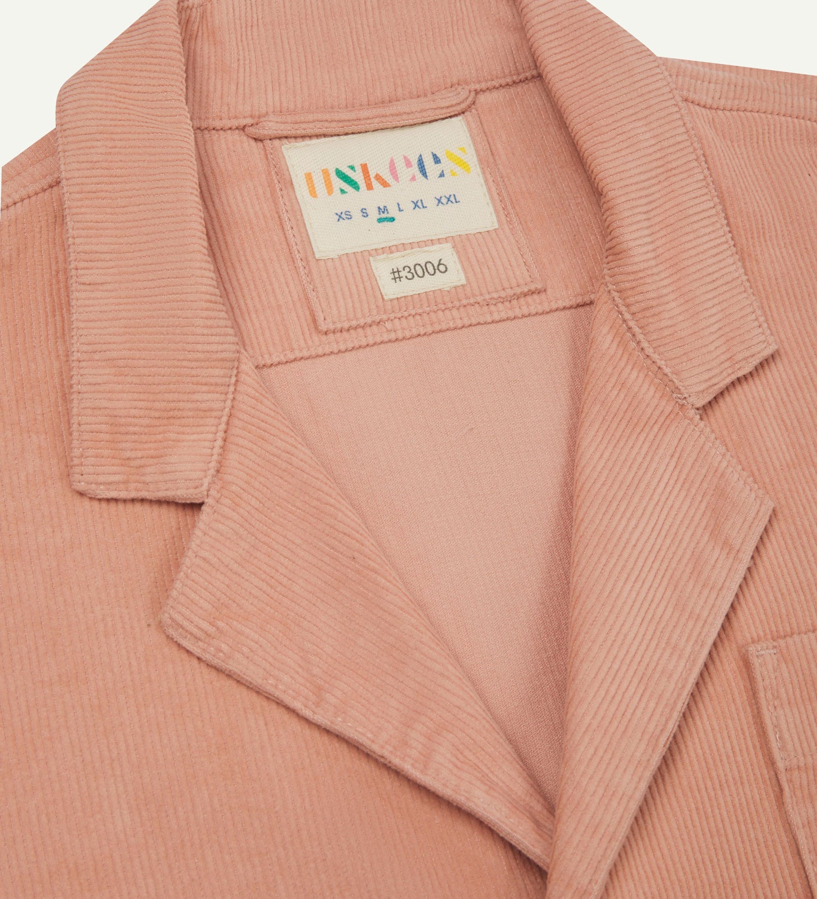 Close-up front view of organic cord 'dusty pink' blazer showing the collar, lapels and Uskees brand label.