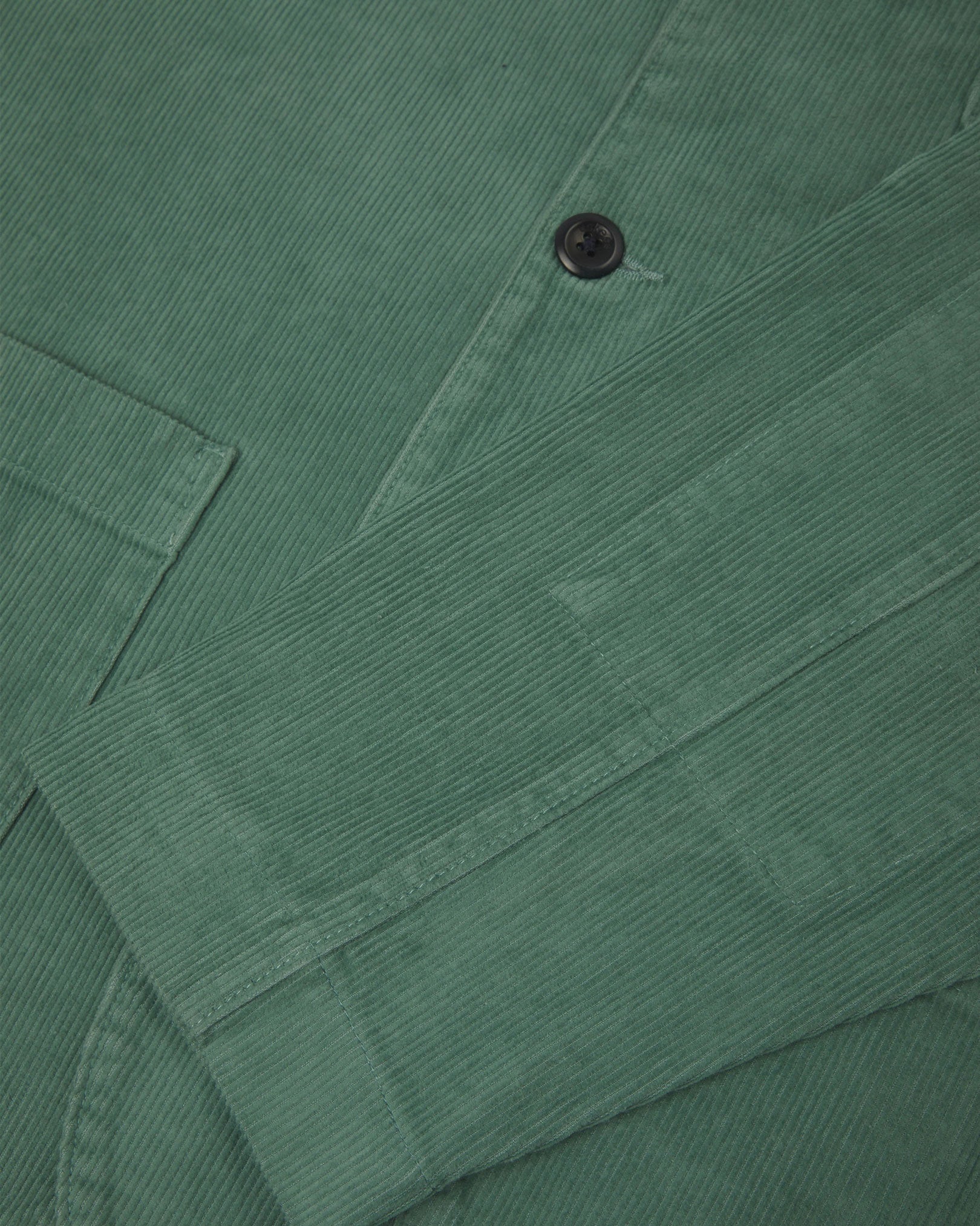 Close-up view of cuff, placket and corozo buttons of organic corduroy, eucalyptus-green blazer from Uskees.