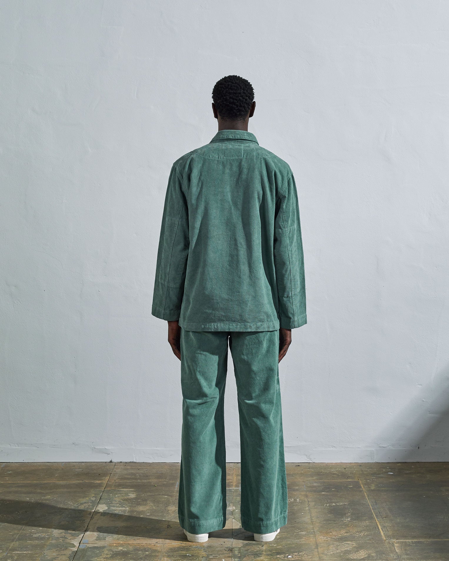 Full length back view of model wearing eucalyptus-green corduroy #3006 Uskees blazer, with view of reinforced elbows and boxy fit.