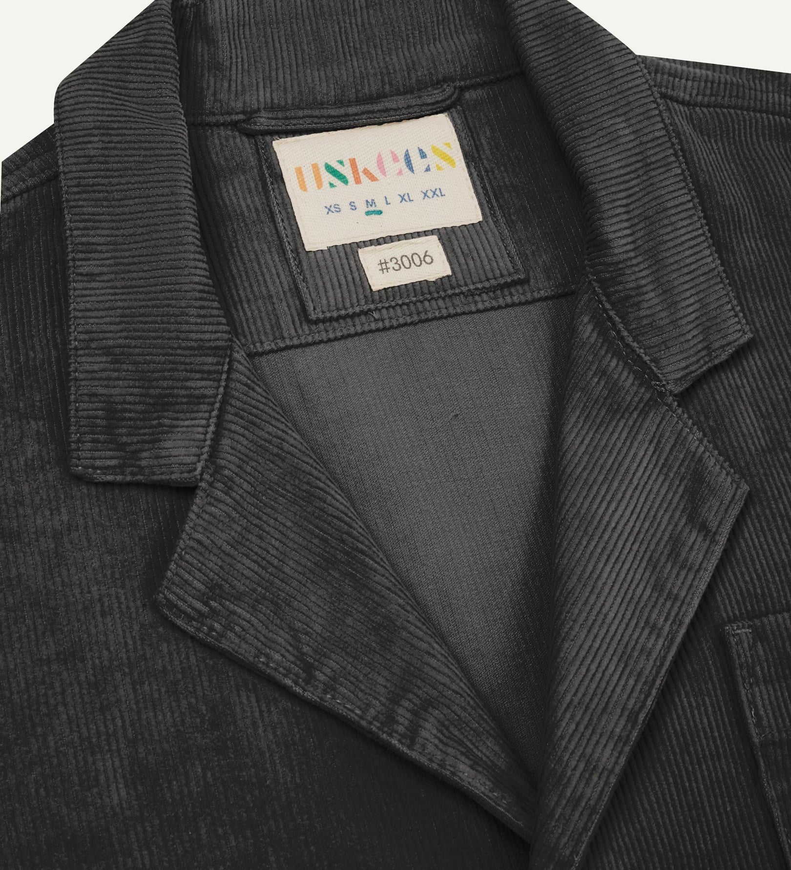 Close-up front view of organic cord faded black blazer showing the collar, lapels and Uskees brand label.
