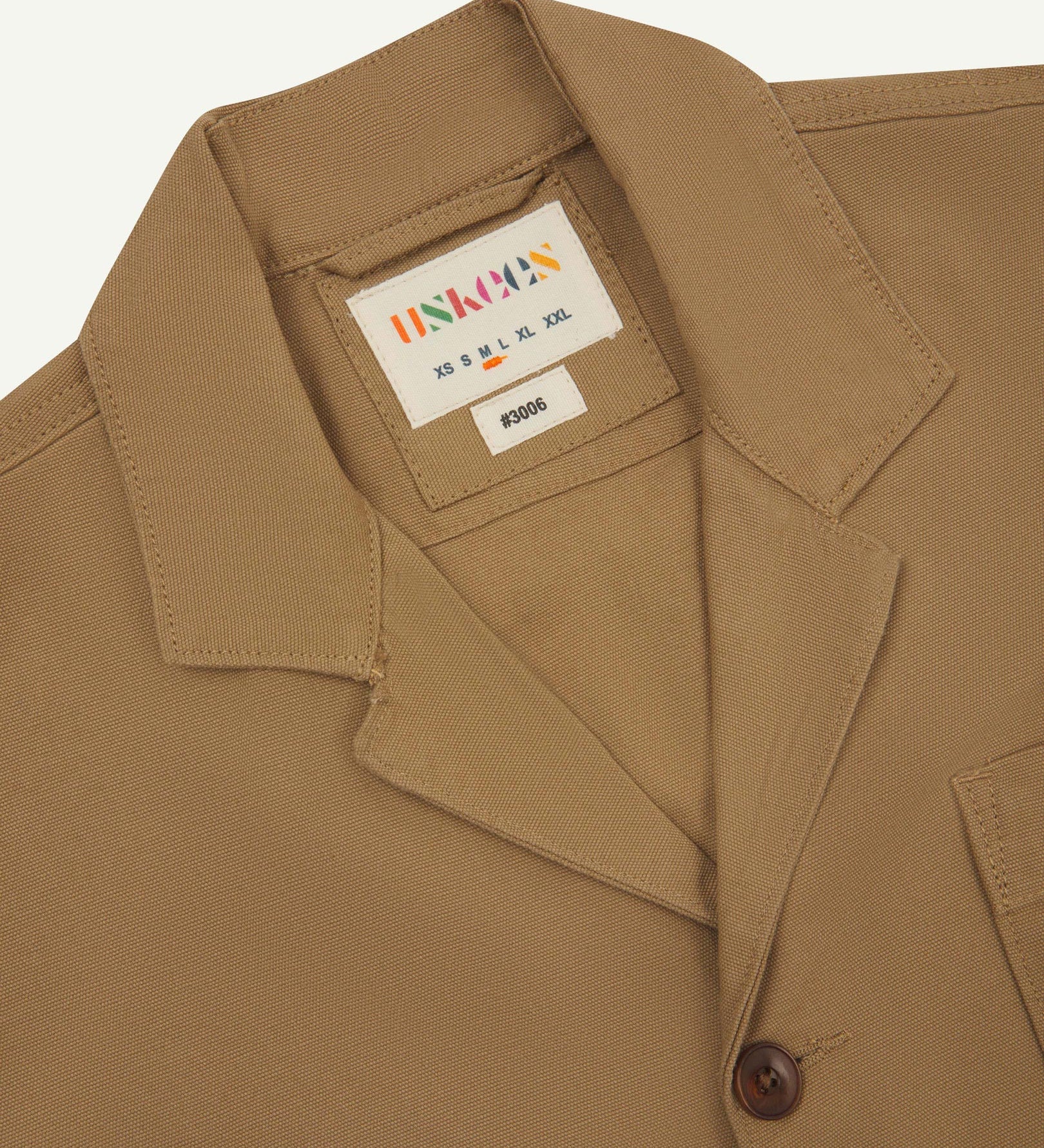 Close-up front view of organic cotton khaki green blazer showing the collar, lapels and Uskees brand label.