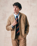 Top-half view of man wearing the 3006 khaki blazer from Uskees. Blazer buttons unsecured, revealing striped Uskees tie.