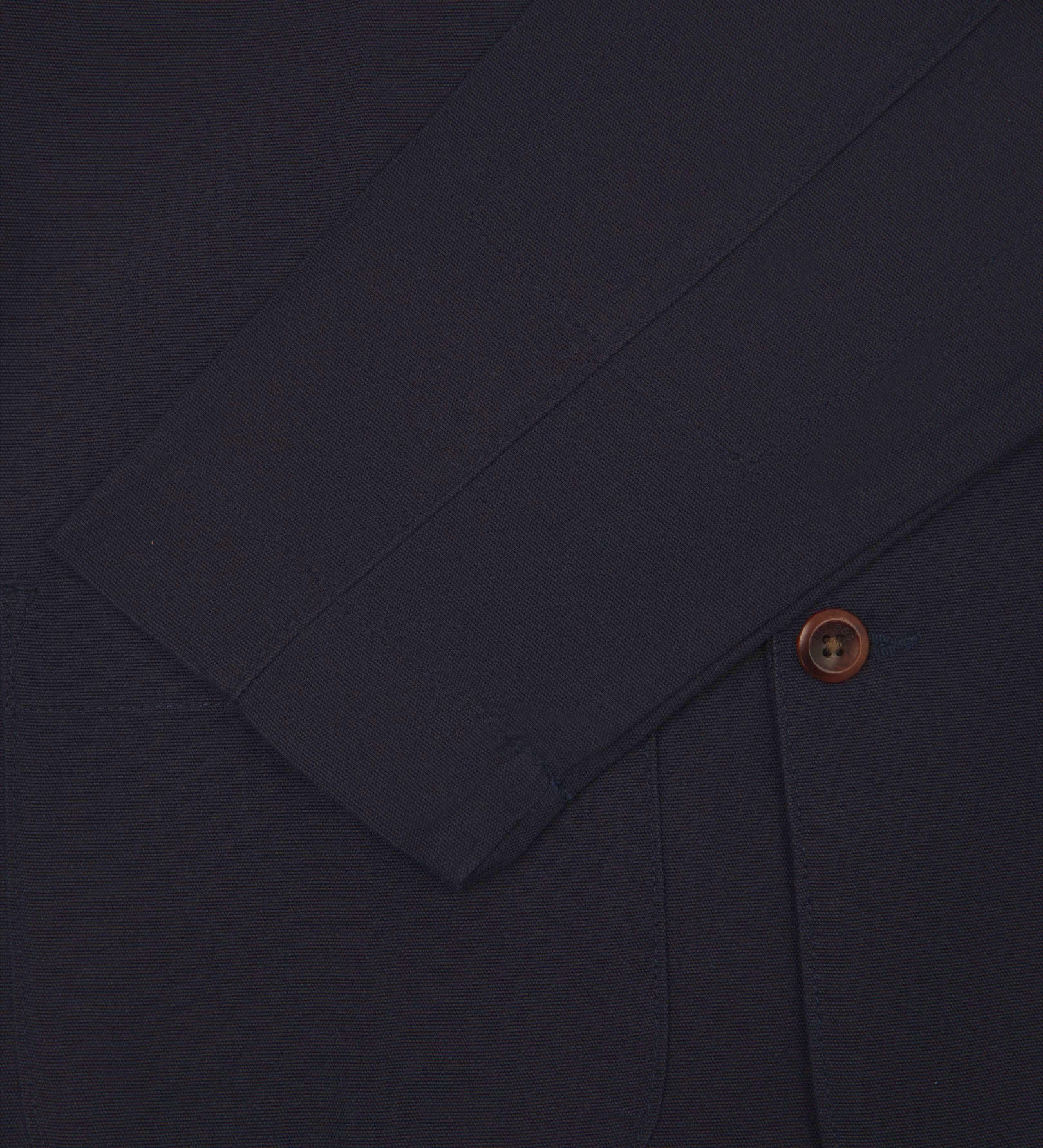 Close-up view of cuff, pocket and button of organic cotton, midnight blue blazer from Uskees.