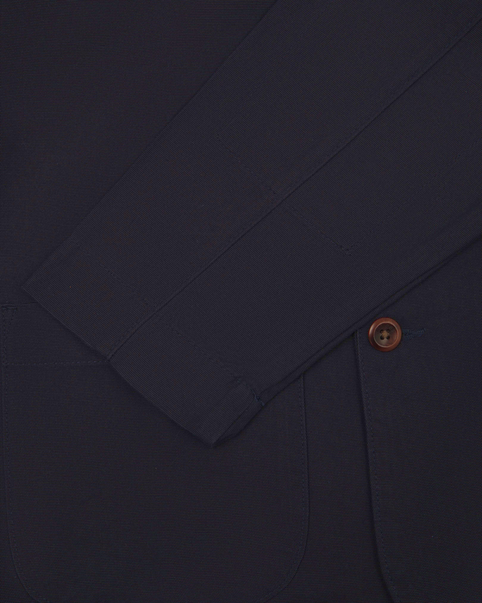 Close-up view of cuff, pocket and button of organic cotton, midnight blue blazer from Uskees.